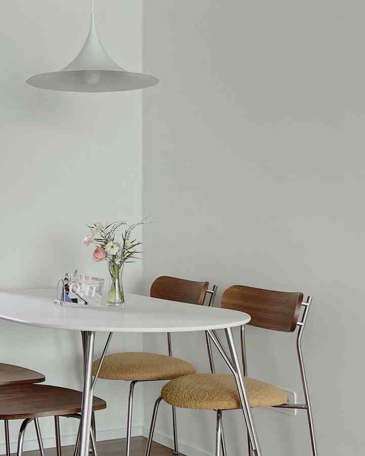 A white and brown toned dining room featuring a simple dining table and chairs arranged neatly