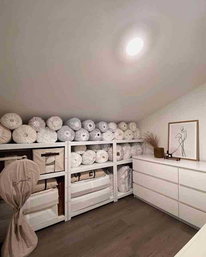 白と木目調の調和がとれたウォークインクローゼット、整頓された布団とチェストが印象的な空間