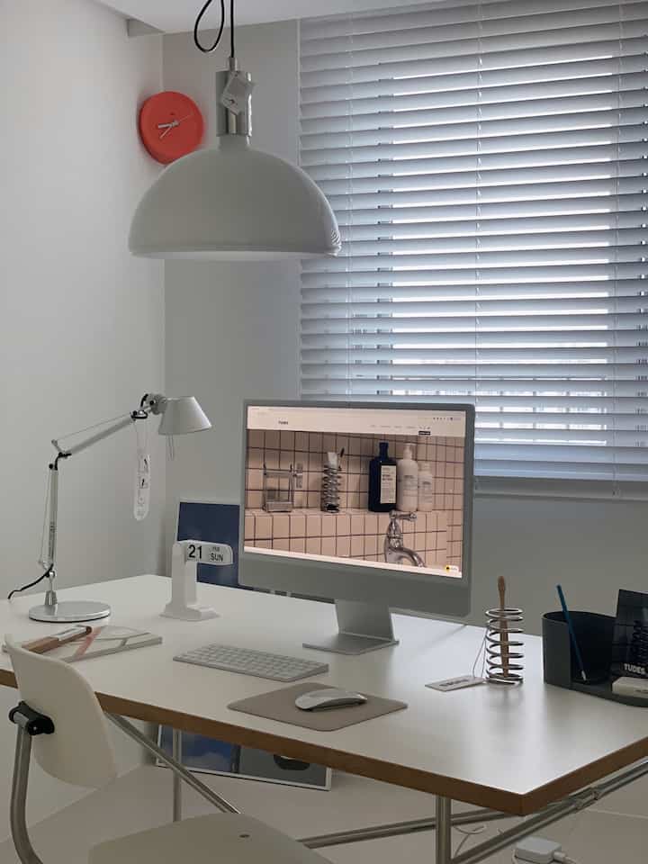 White and natural tone home office featuring a desk with computer and pendant light in a clean modern setting