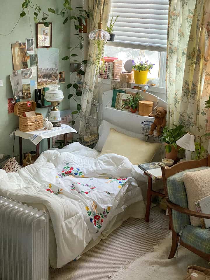 白とベージュの色調の寝室、花柄のカーテンと刺繍の布団が配置された雰囲気のあるヴィンテージインテリア