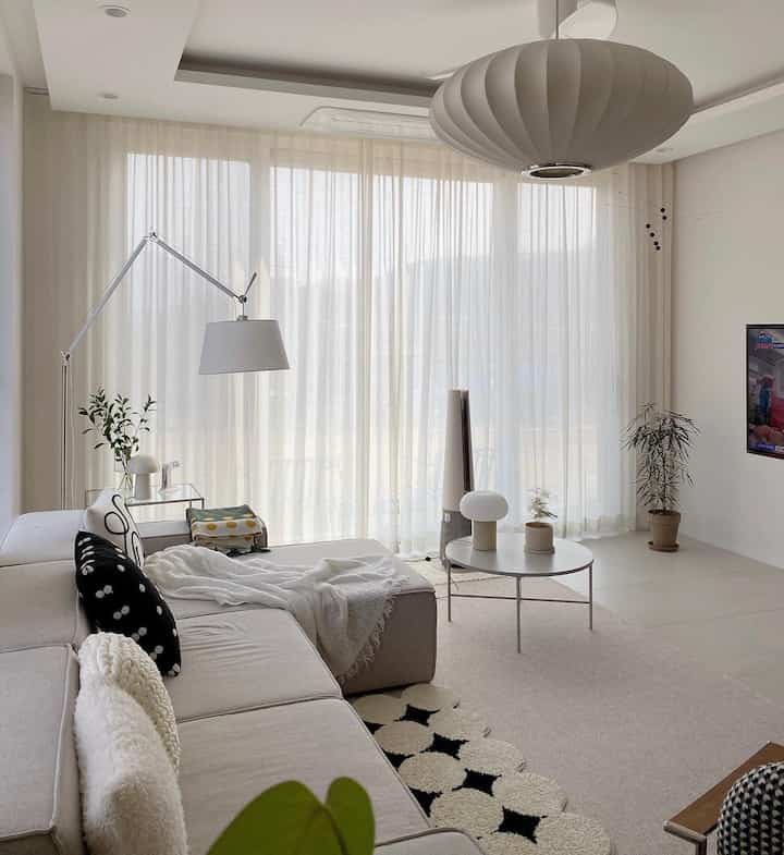 A soft ivory curtain and beige modular sofa arranged in a simple, natural styled living room