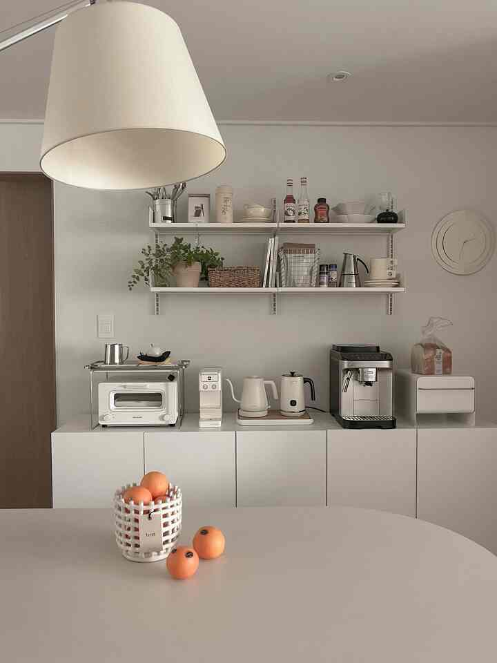 Minimal and natural toned kitchen featuring organized shelves, coffee machines, and white cabinetry creating a cozy home cafe atmosphere