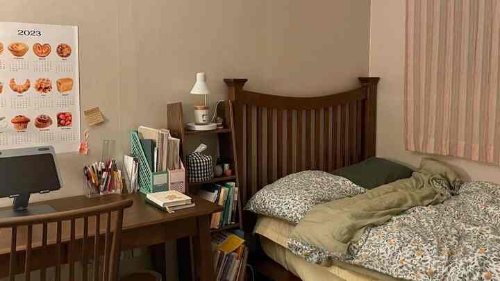 ブラウンの木製ベッドとデスクを備えたナチュラルカラーの6畳寝室、柔らかなベージュの壁とストライプのカーテンが調和する落ち着いた空間