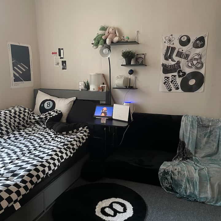 Gray and black toned studio bedroom featuring checkered bedding and black sofa in a modern interior