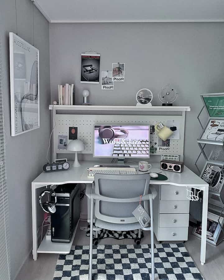 Gray and white toned compact home office study space featuring clean desk and chair with mid-century modern posters and decor