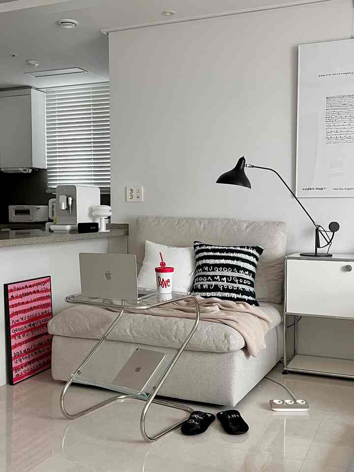 Natural-toned living room featuring beige sofa, glass coffee table, and black table lamp in a simple layout
