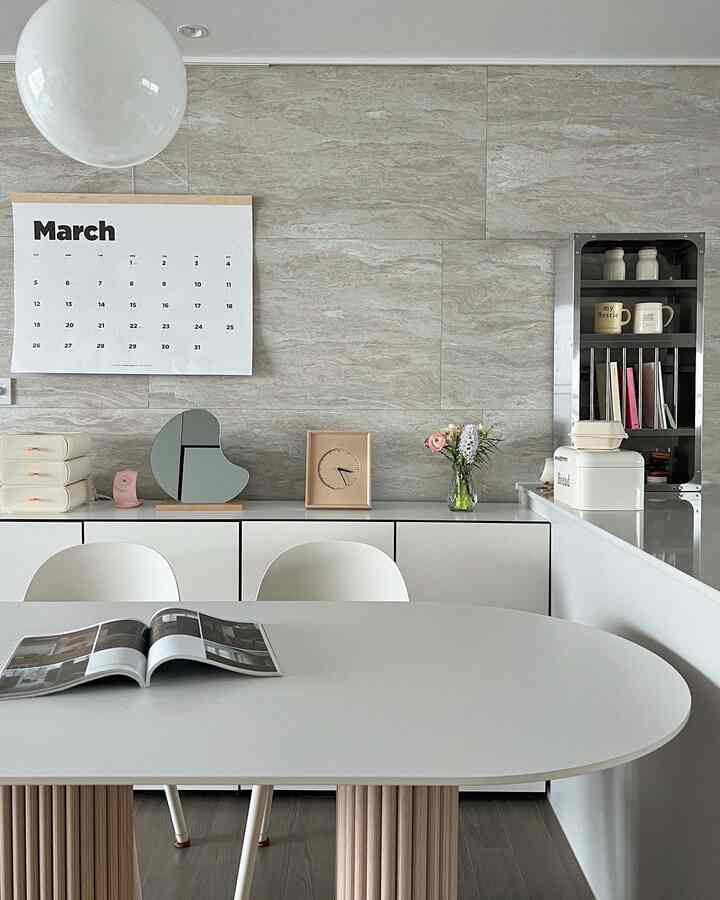 Beige tiled wall and white dining table with chairs in a simple kitchen space