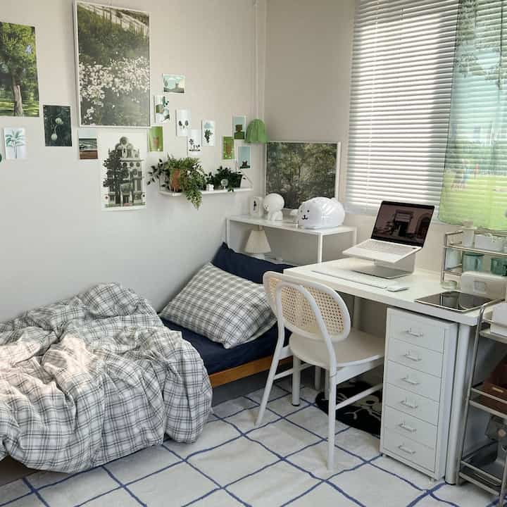 A small modern bedroom dominated by white and blue tones featuring a desk and a single bed with neat decor