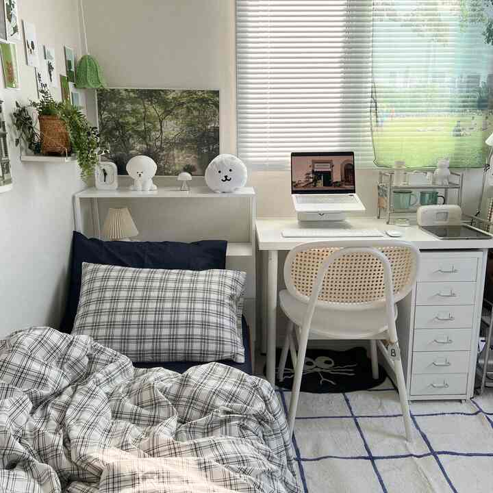 White and navy toned single bedroom featuring a bed and desk arranged cozily in a natural modern style