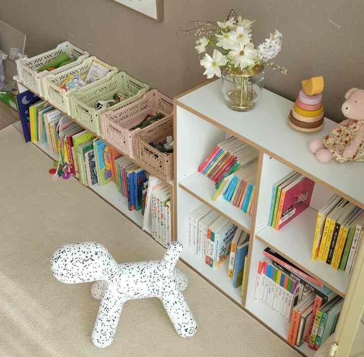 Beige and white toned kids' room featuring bookshelves, storage boxes, and natural decorative elements