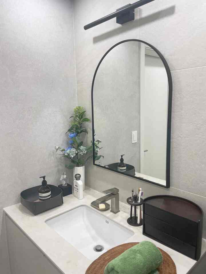 Bright white and black toned powder room featuring a sink and large black-framed mirror in a clean layout