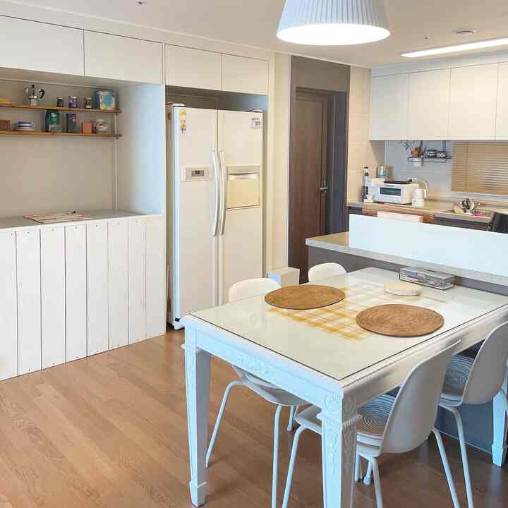 白とナチュラルな木目調が調和したダイニングルーム、清潔感のある白いダイニングテーブルと椅子が配置された落ち着いた空間