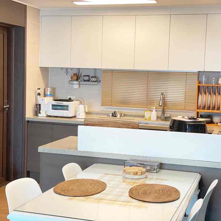 White and brown toned kitchen with a clean layout featuring a dining table with rattan placemats