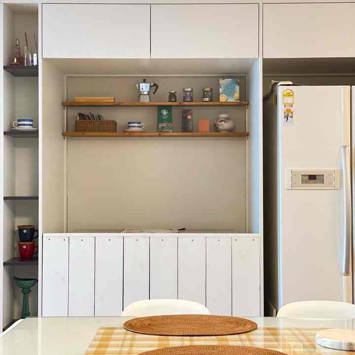 White and wood tone kitchen space featuring wooden shelves and rattan pattern baskets, creating a minimal and natural dining room atmosphere