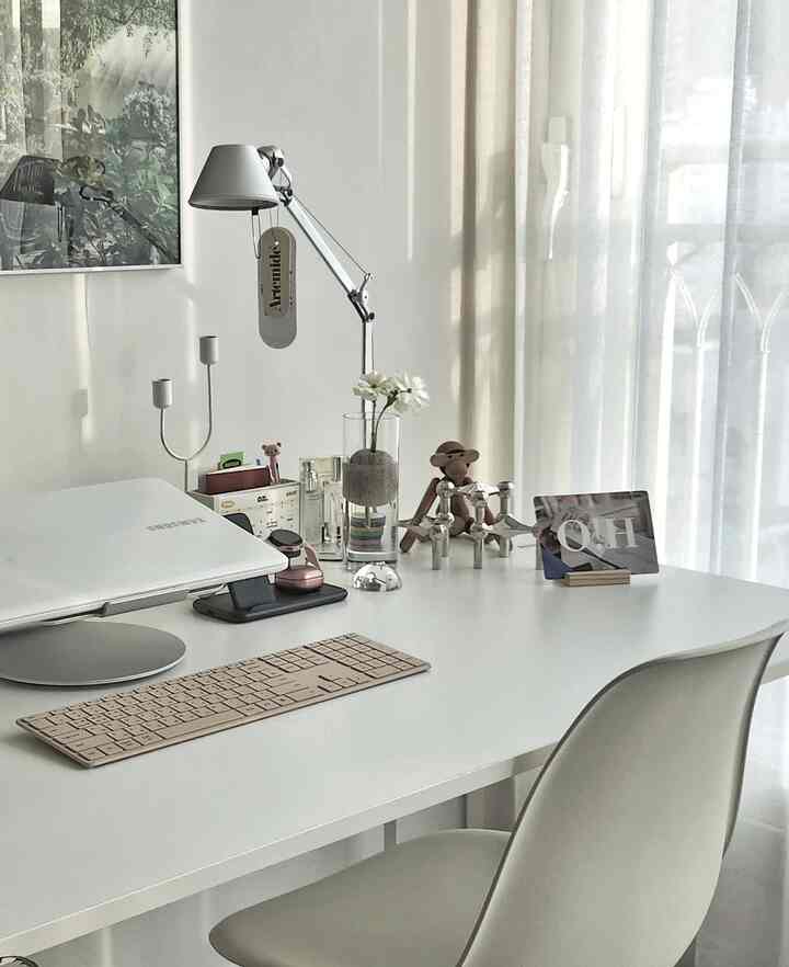 White tone home office space featuring a neatly organized desk, office chair, and table lamp with minimalist style