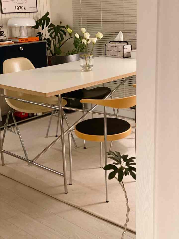 White-toned dining room featuring a central dining table and chairs in a clean, modern setting