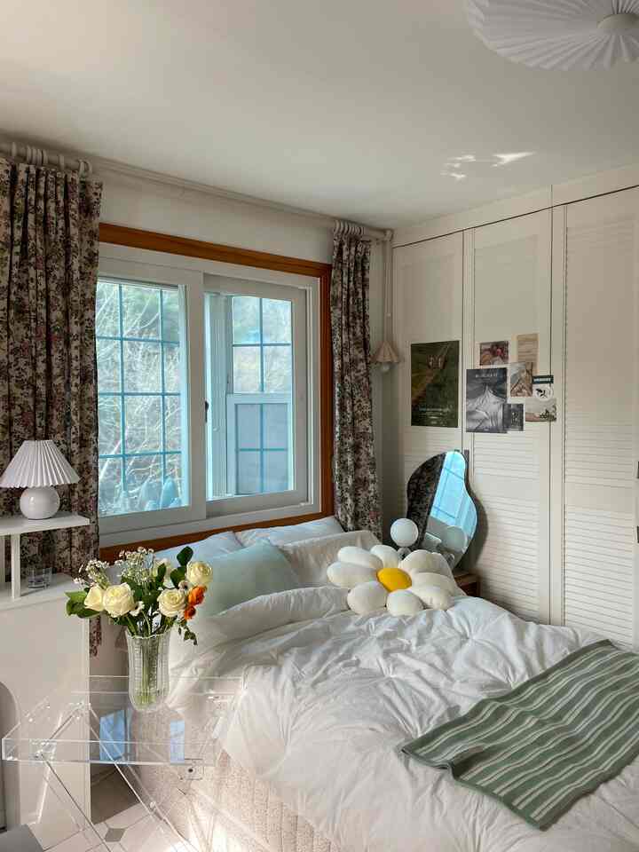 A 6-tatami bedroom in white and beige tones featuring floral patterned curtains and a daisy cushion, creating a cozy atmosphere