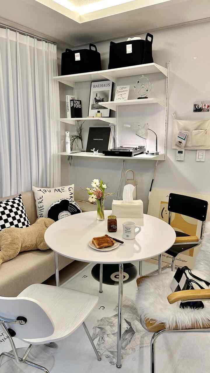 White-toned small dining space featuring beige sofa and round table arranged in a cozy home cafe style interior.