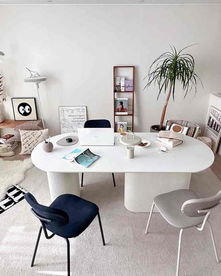 White and navy toned home office featuring a modern simple desk and chairs, bookshelf and plant creating a cozy atmosphere