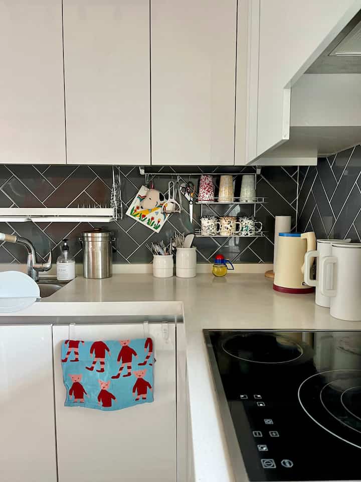 白とグレーのトーンが印象的なモダンなキッチン、清潔感のあるシンクエリアと整頓された調理器具が配置された雰囲気のあるインテリア