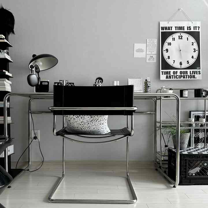 Black and white toned Mid-Century Modern study featuring chrome frame armchair and desk in a clean, sleek design