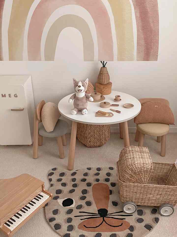 柔らかなナチュラルトーンの子供部屋、木製テーブルとおもちゃ、クマ形ラグが配置された温かみのある空間