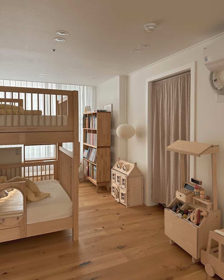 A cozy kids' room featuring warm wood tones and white walls, wooden bunk bed, bookshelf, and toy organizer neatly arranged