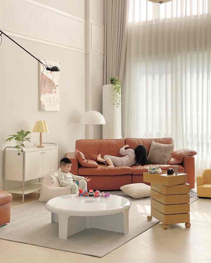 Beige and brown toned living room featuring a brown leather sofa and children playing in a cozy space