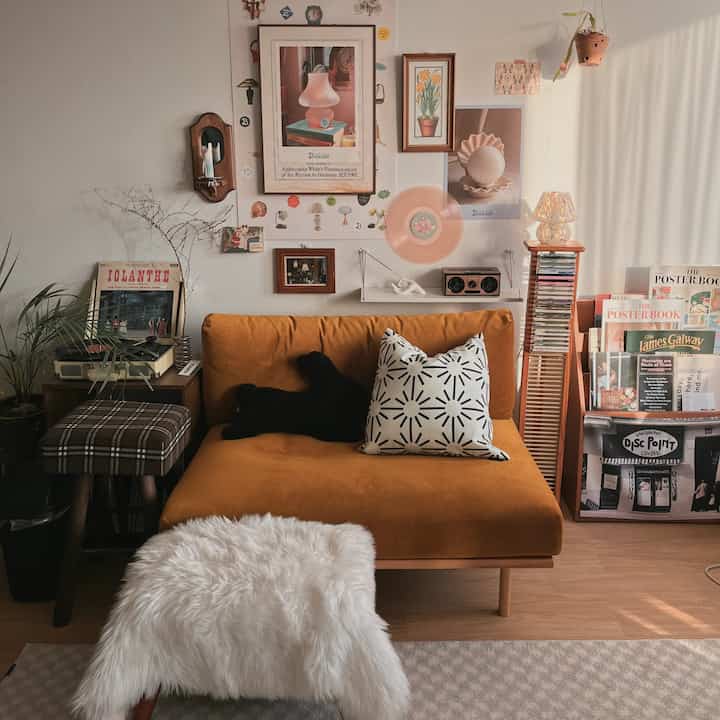 Warm beige-toned living room featuring a mustard orange sofa and vintage decorations with wall art and records.