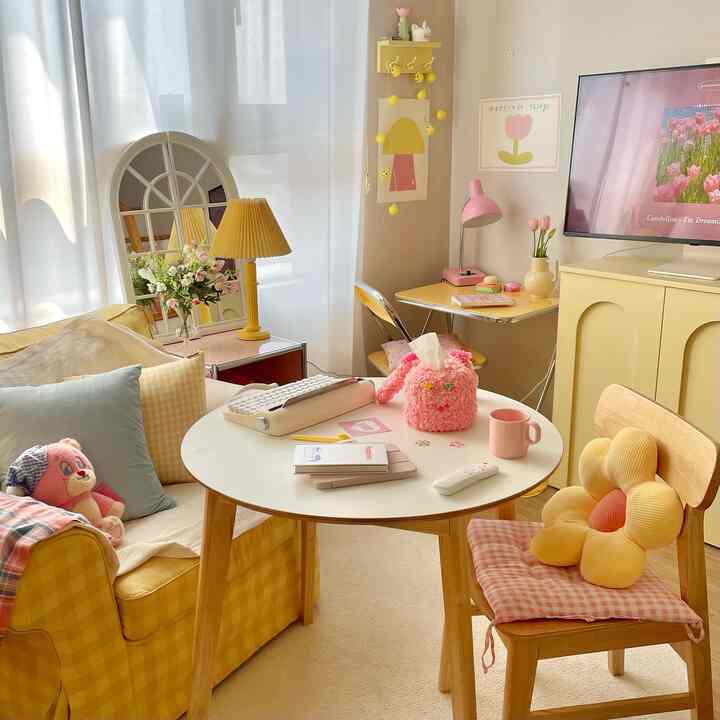 Yellow and pink accented studio living room featuring a round table and arched mirror with bright spring atmosphere