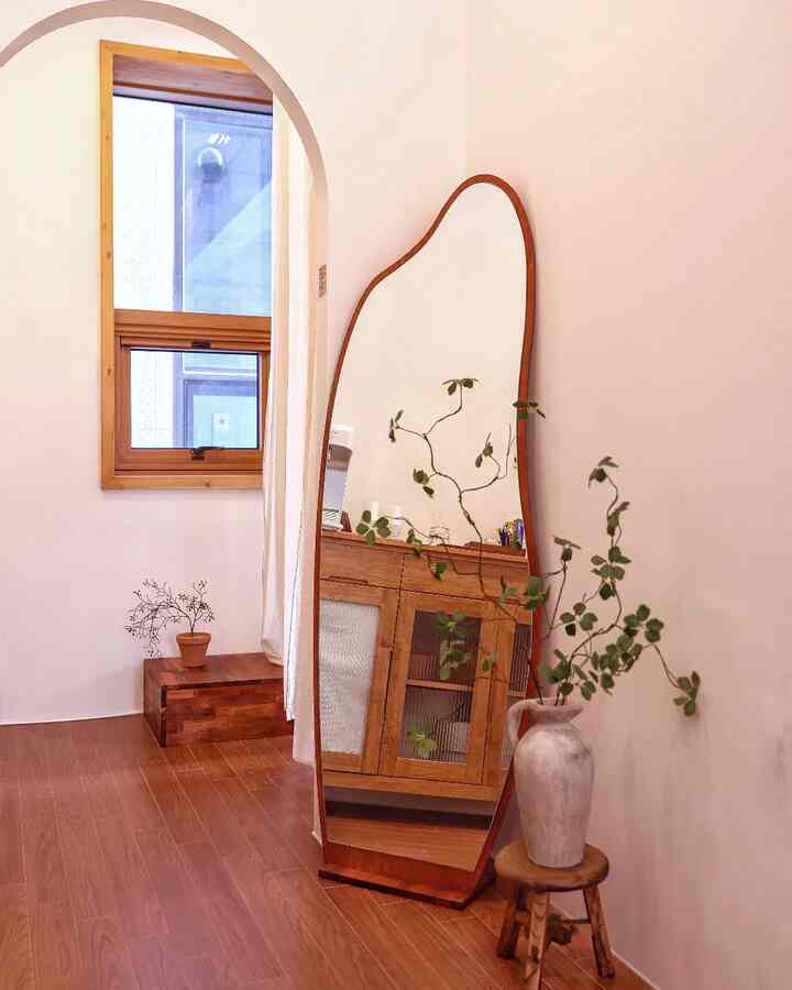 木目調でナチュラルなウォークインクローゼット、曲線的な非定形木製全身鏡と植物が配置された雰囲気のあるインテリア