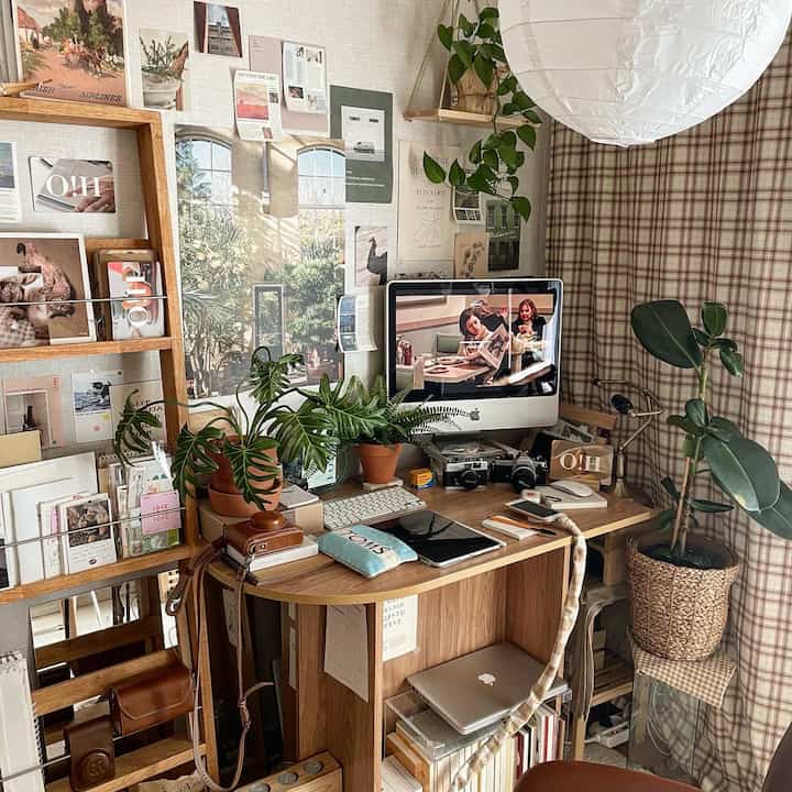 Cozy home office space with warm wood tones and vintage vibes, featuring various plants and posters