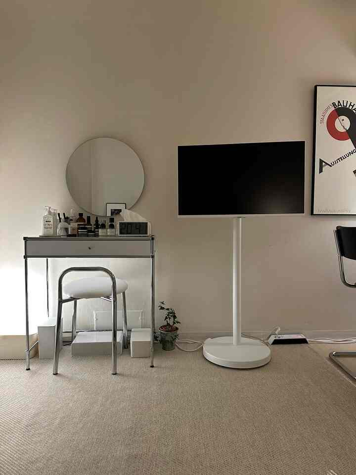 White tone living room featuring a chrome stool, vanity table, and monitor stand with a simple and clean interior design