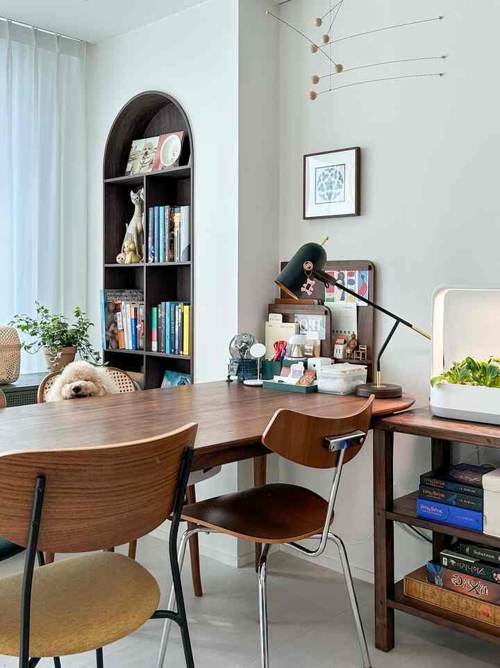 White walls and wood-toned furniture in a living room featuring a dining table, chairs, and a dog in a natural modern style space