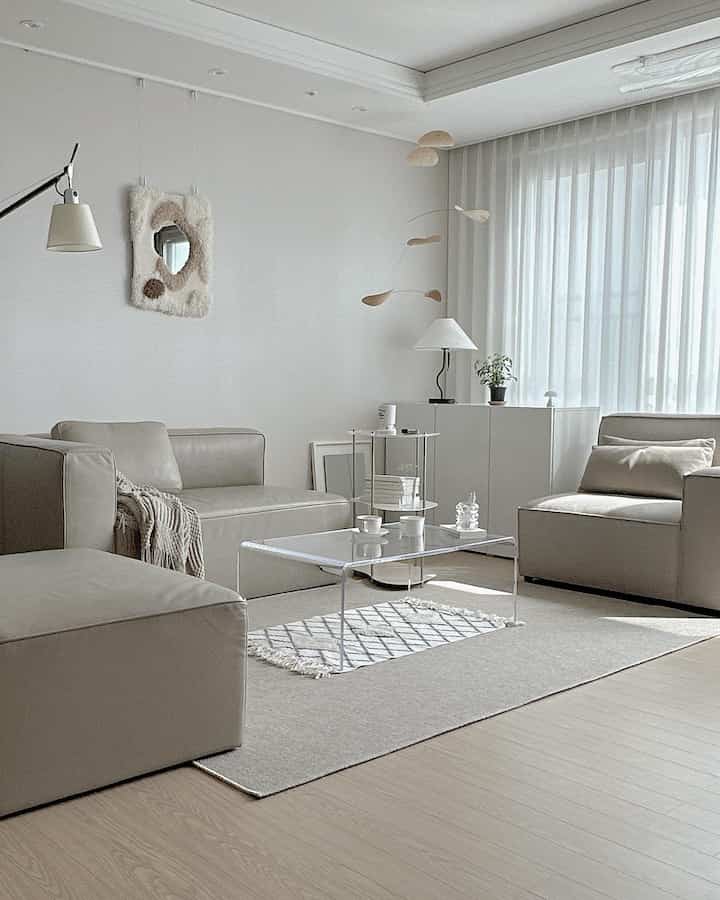 Beige and white natural modern living room featuring modular sofas and a transparent coffee table in a cozy arrangement