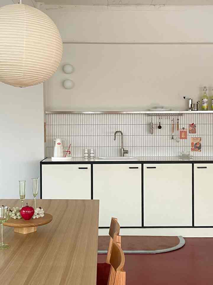 白と木目調のモノトーンキッチン、シンプルで清潔感のあるダイニングテーブルが配置された雰囲気のある空間