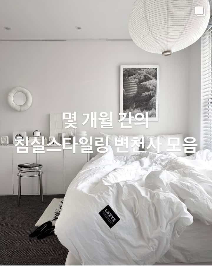 ホワイトとモノトーンの色調の寝室、中央に白い掛け布団カバーのベッドと壁に額縁が配置されたシンプルな空間