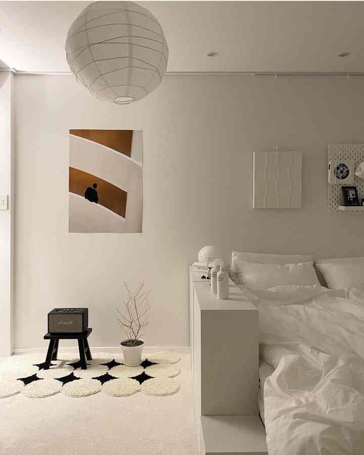 White-toned bedroom space featuring a minimal hotel-like bed setup with neat decor and furnishings