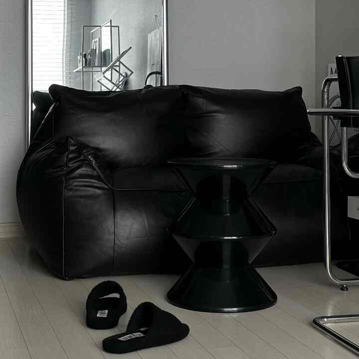 Monotone natural interior featuring a black bean bag sofa and side table with light wood flooring