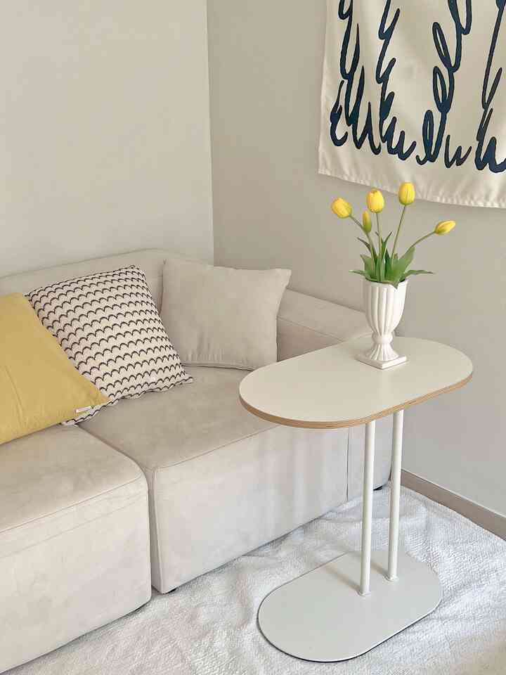 White and yellow toned studio living room featuring a simple sofa and side table with cozy atmosphere