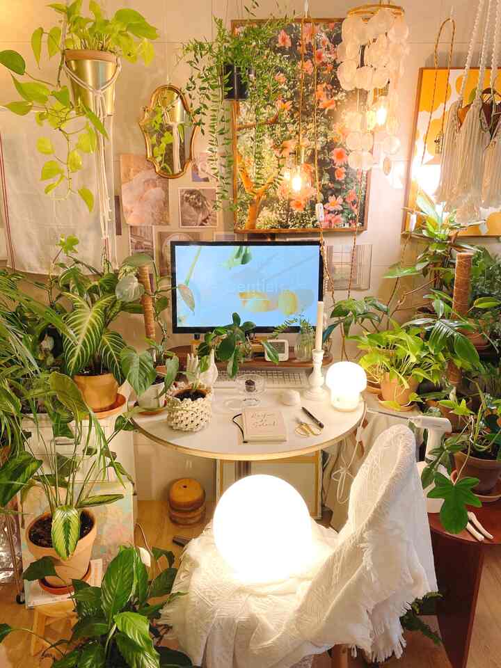 Cozy home office with warm white tones and natural wood flooring, filled with lush green plants and vintage mirrors