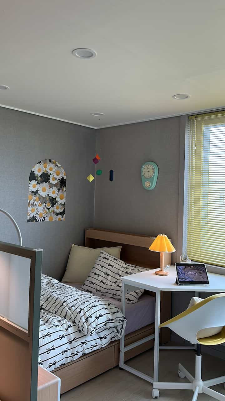 A white and wood tone bedroom featuring a corner desk and cozy lamp, creating a modern and warm atmosphere