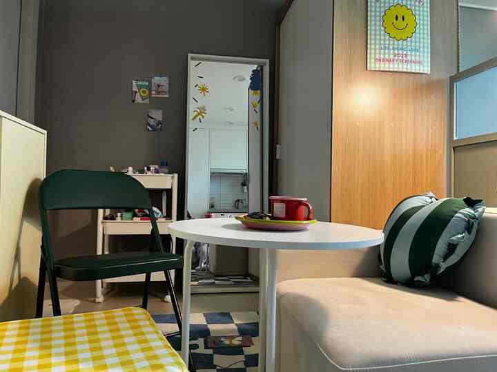 White and green toned walk-in closet and home cafe space featuring sofa, stools, and full-length mirror in a cozy cafe-style room