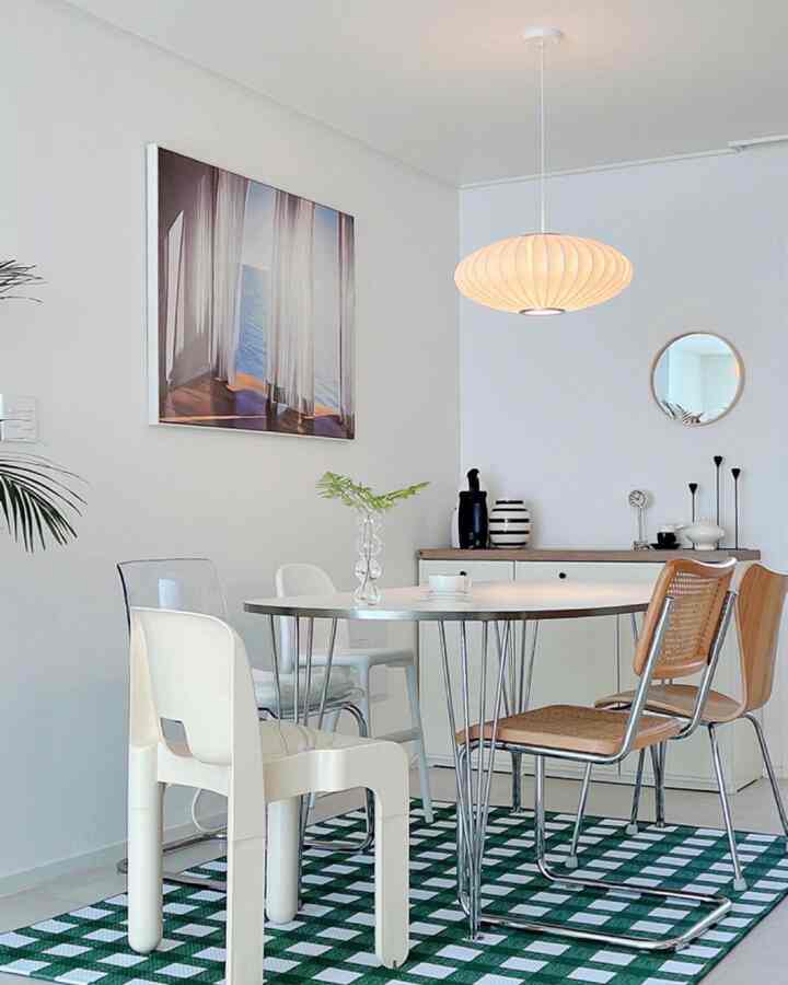 白と木目調のダイニングルーム、丸テーブルと様々な椅子が配置されたシンプルでモダンなインテリア