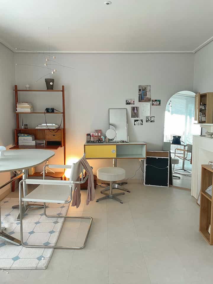 Modern living room and home office with white and wood tones, featuring minimal furniture and ambient lighting