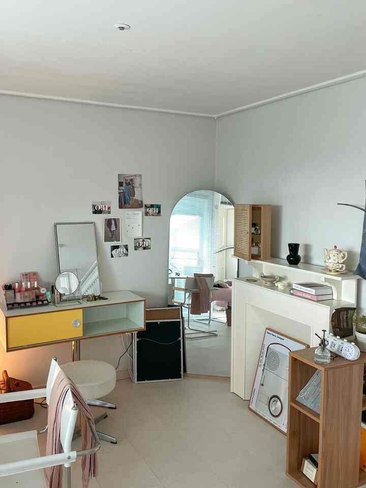 Natural tone and white dominated living room featuring round full-length mirror and yellow vanity creating a simple atmosphere