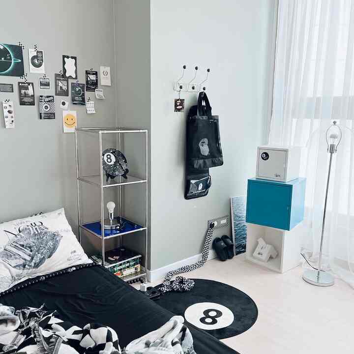 Gray and black toned bedroom featuring a black 8-ball rug and modern metal shelving, creating a simple and minimal atmosphere