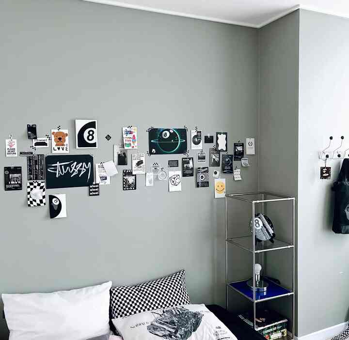 グレーの壁とモノトーンの枕があるリビング、壁には多様な白黒のウォールデコが配置されたシンプルで現代的なインテリア