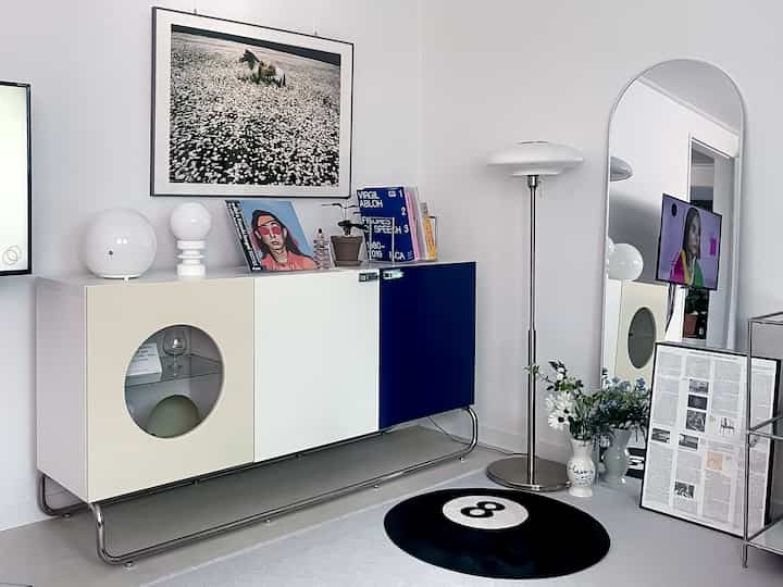 ホワイトとブルーのトーンのミッドセンチュリーモダンなホームオフィス空間に、ビアークのキャビネットと照明、ラグが配置された印象的なインテリア