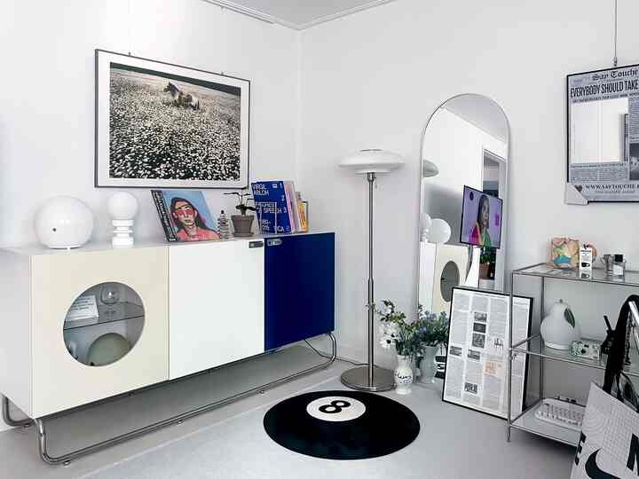 ホワイトとブルーの色調のリビングルーム、大型チェストと全身鏡、フロアランプが配置されたモダンなインテリア